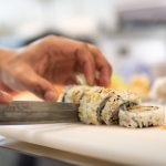 Sushi biter blir skåret på et brett